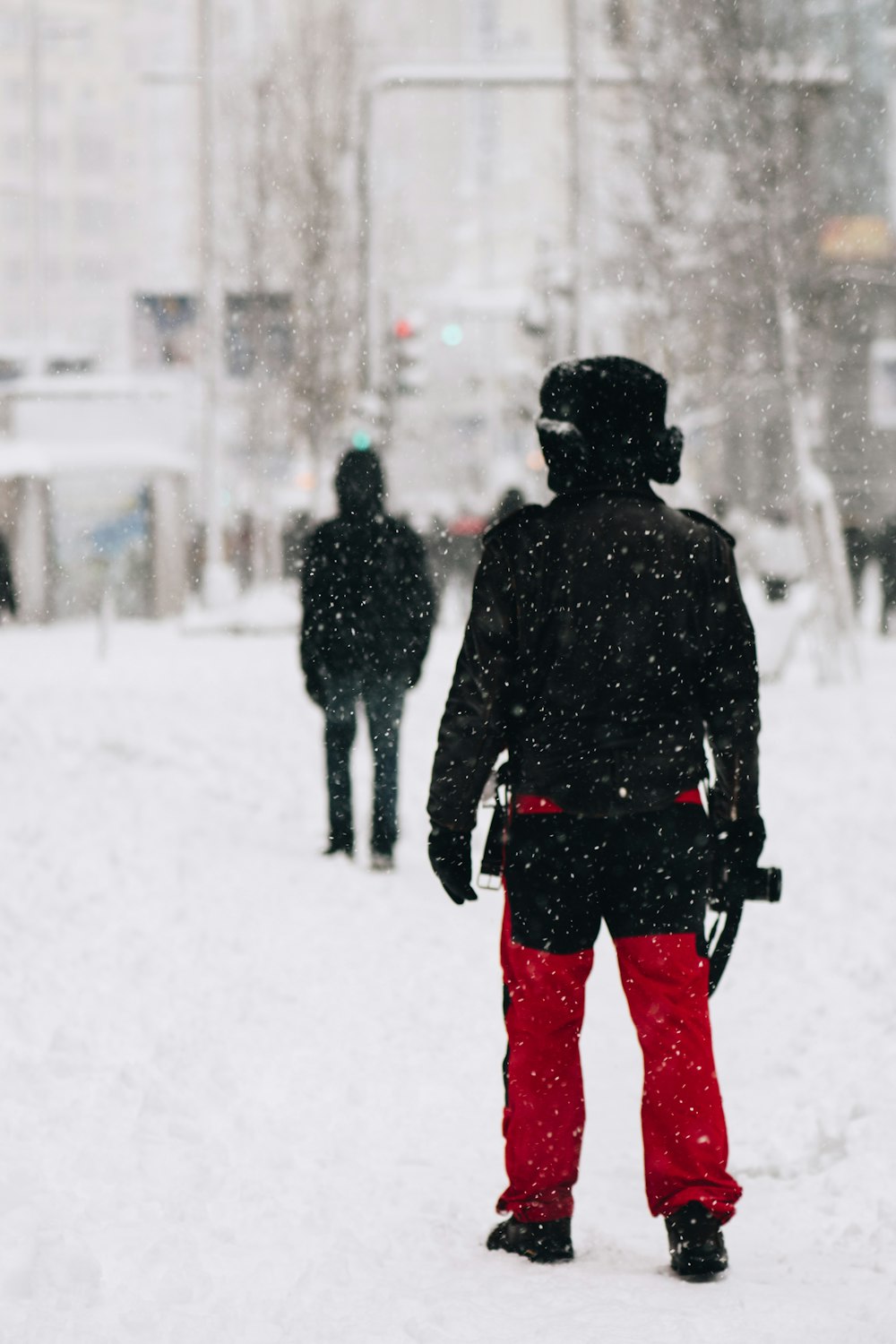 man in black jacket and red pants standing on snow covered ground during daytime