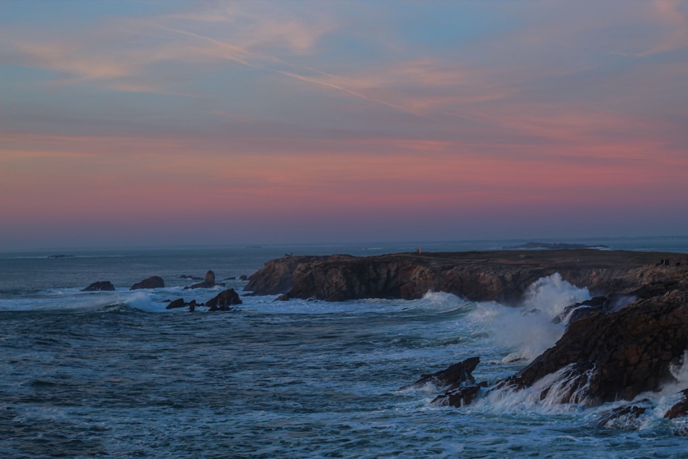 Olas del océano rompiendo contra las rocas durante la puesta de sol