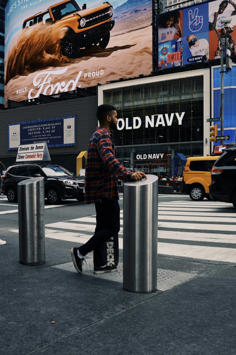 man in brown and black plaid dress shirt and black pants standing on pedestrian lane during