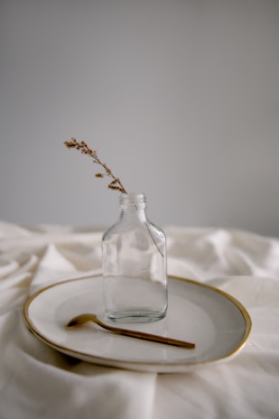 clear glass bottle on white textile