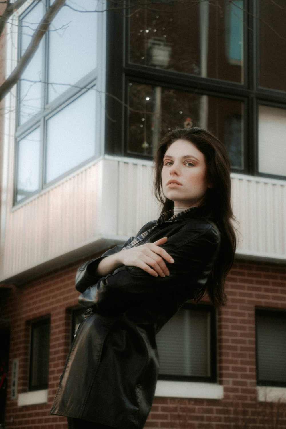 woman in black leather jacket standing near brown concrete building during daytime