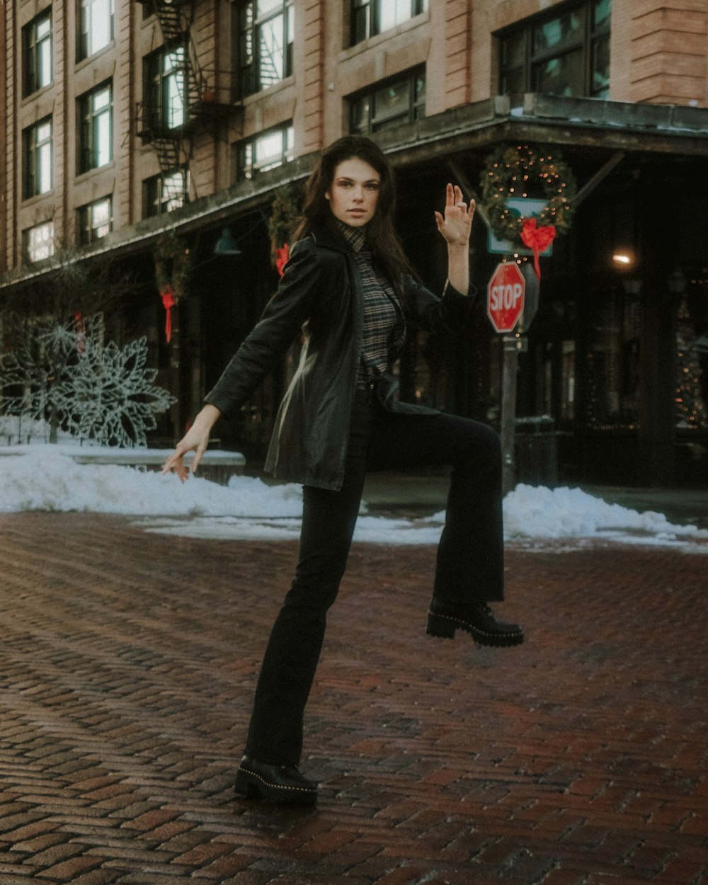 woman in black leather jacket and black pants standing on brown brick floor during daytime