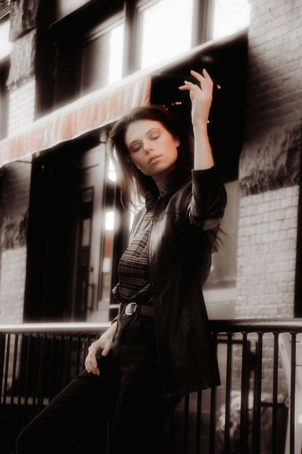 woman in black leather jacket standing beside concrete wall