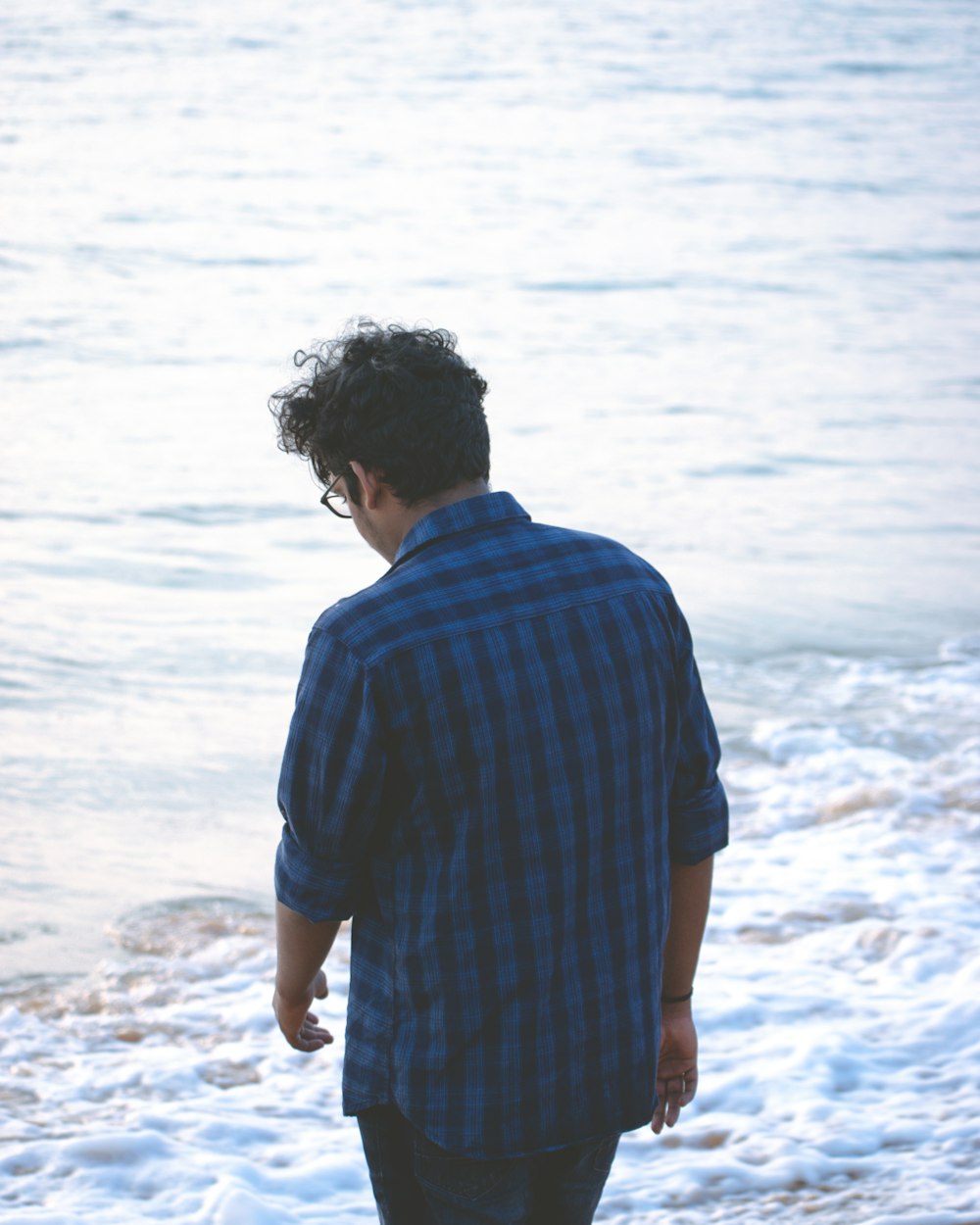 man in blue and white stripe shirt standing on beach during daytime