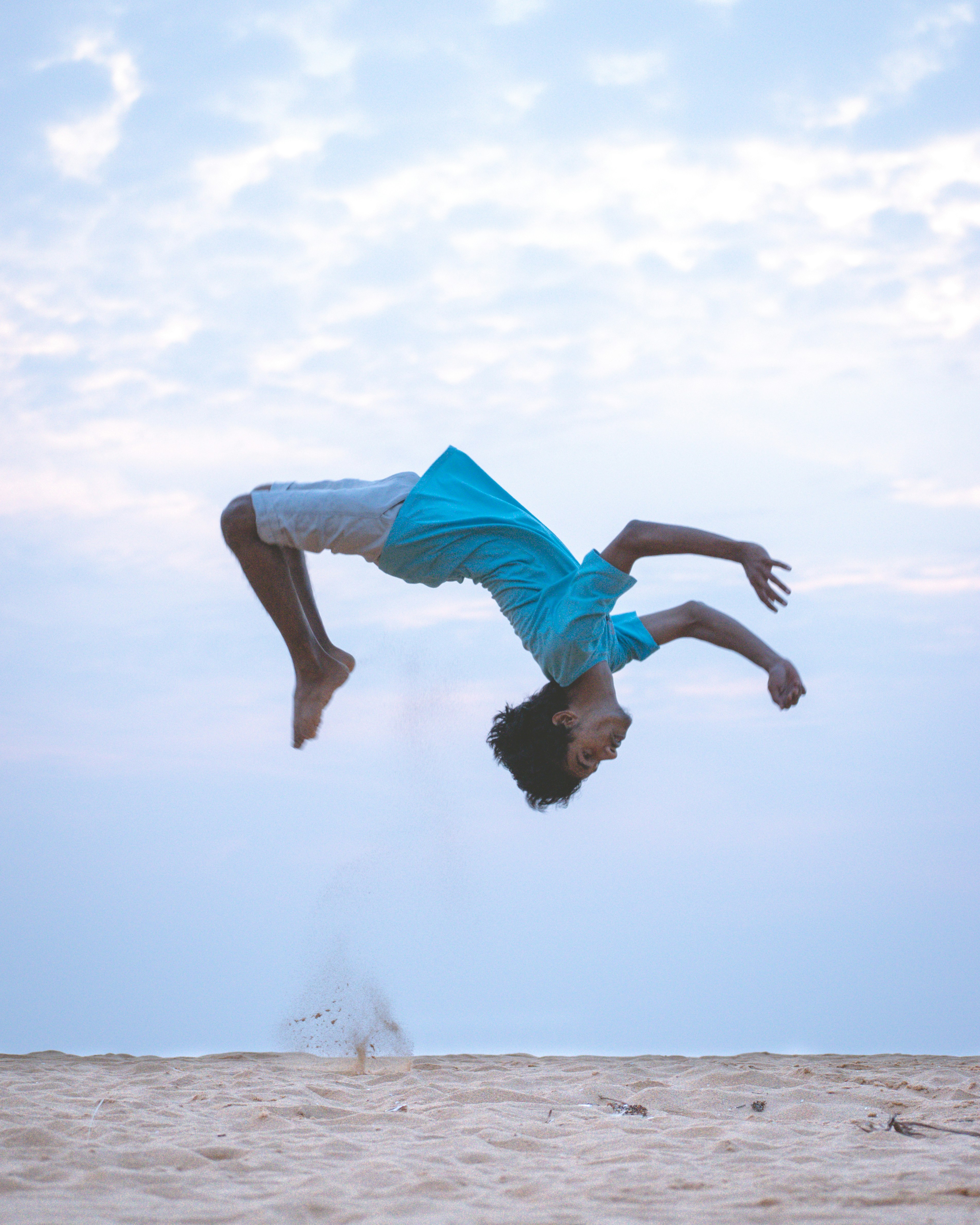 man in blue shorts jumping on beach during daytime