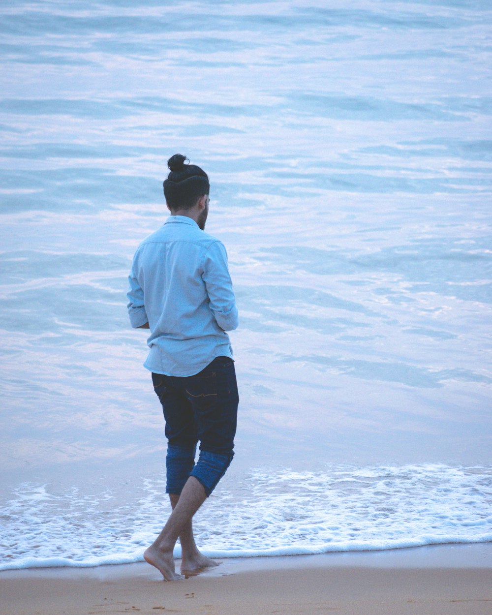 man in white dress shirt and black shorts standing on white sand during daytime