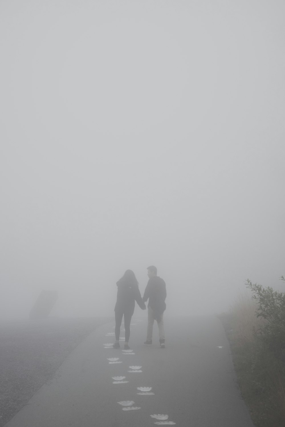 2 men walking on road during foggy weather