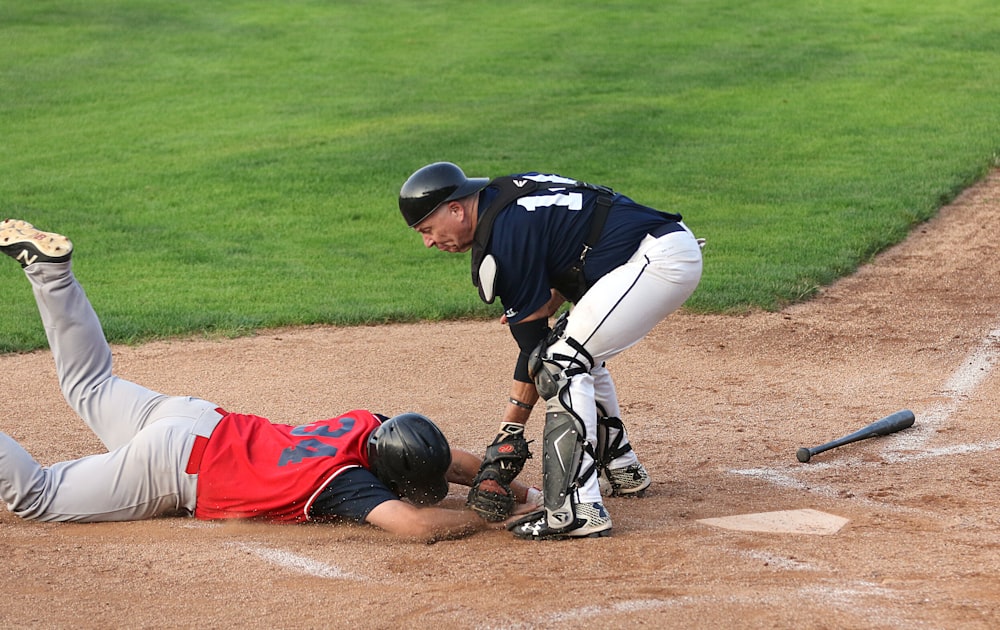 man in red and white jersey shirt and white pants playing baseball during daytime