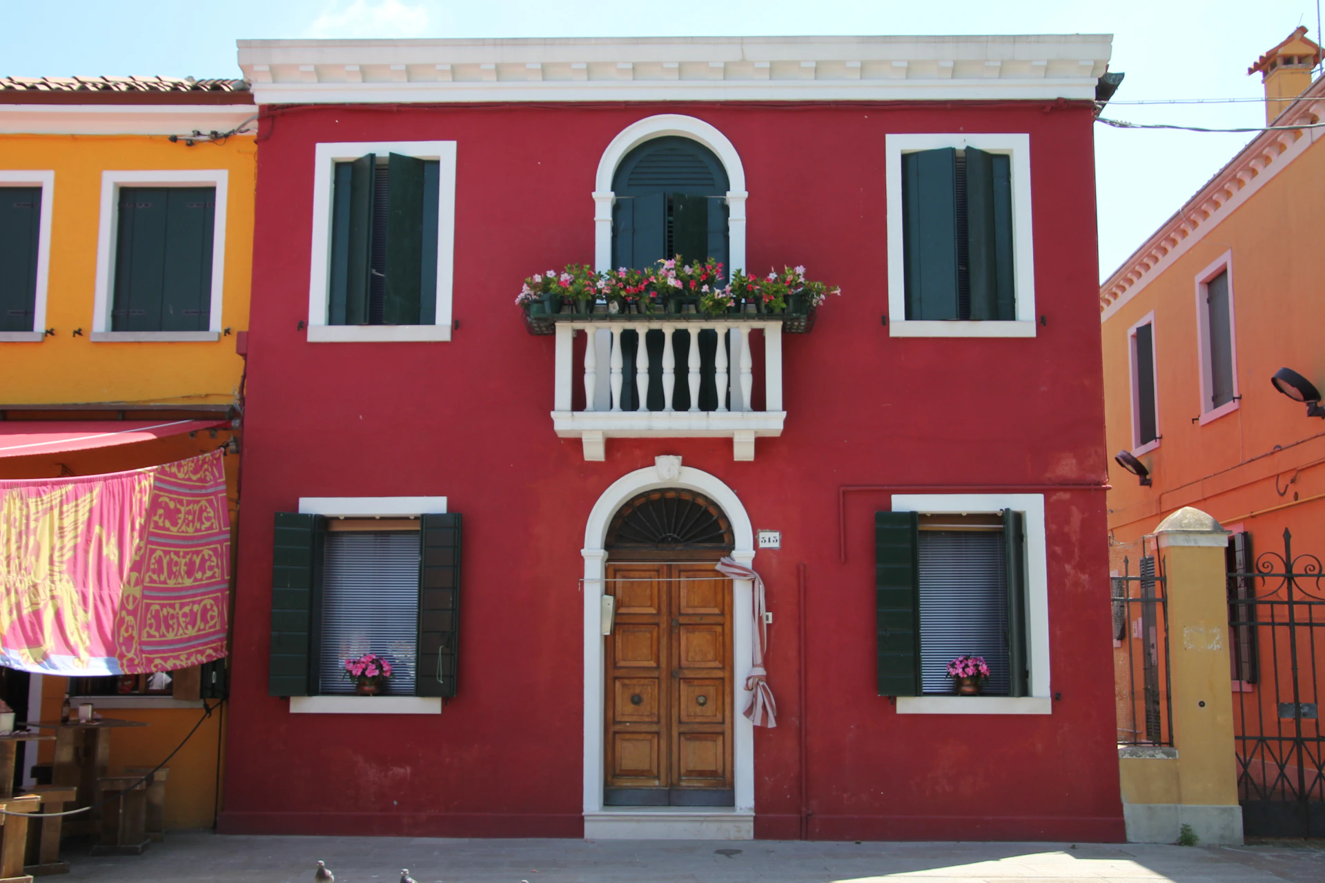 Before and after view of a traditional Alicante home facade freshly painted in deep crimson and forest green accents.