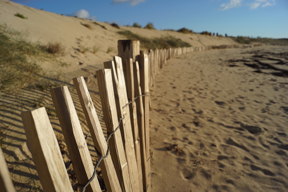 brown wooden fence on brown sand during daytime