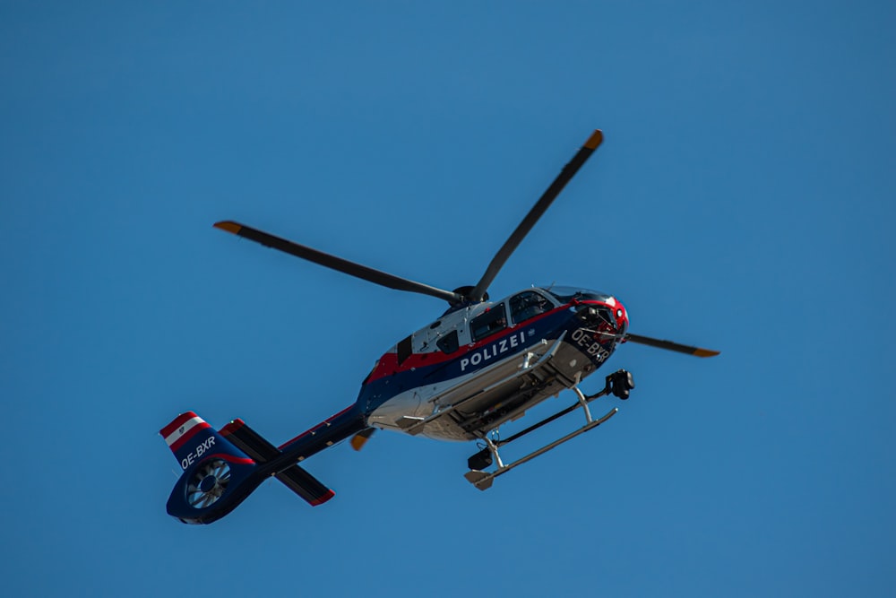 red and white helicopter flying in the sky