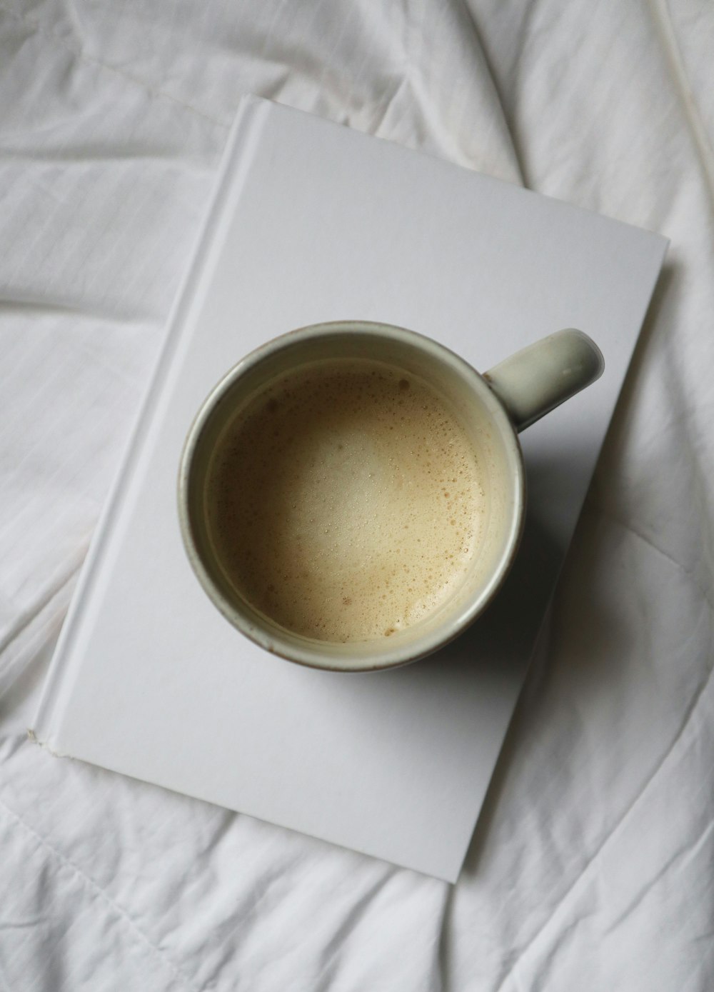 white ceramic mug on white textile