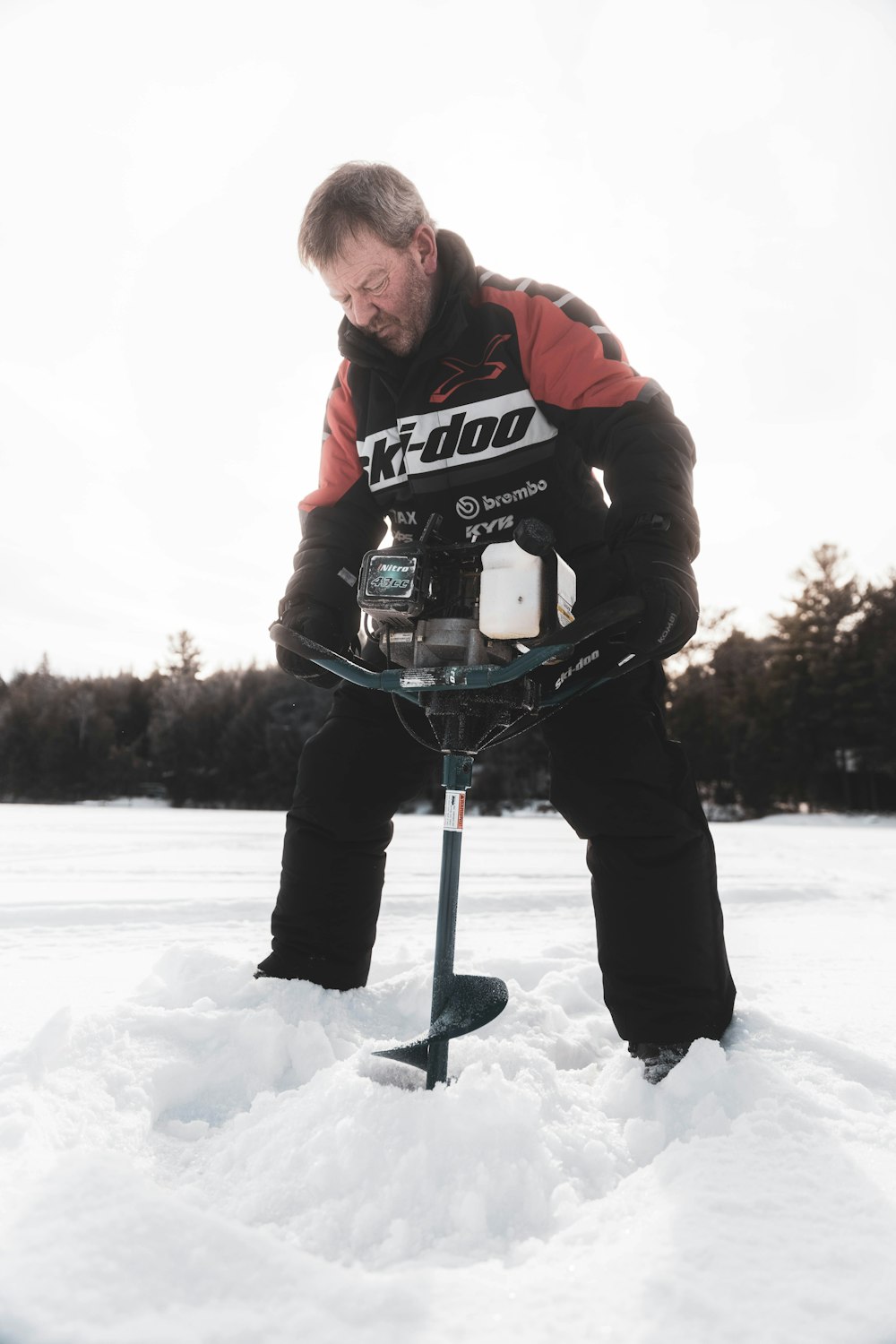 man in red jacket and black pants holding black and white snow ski stick