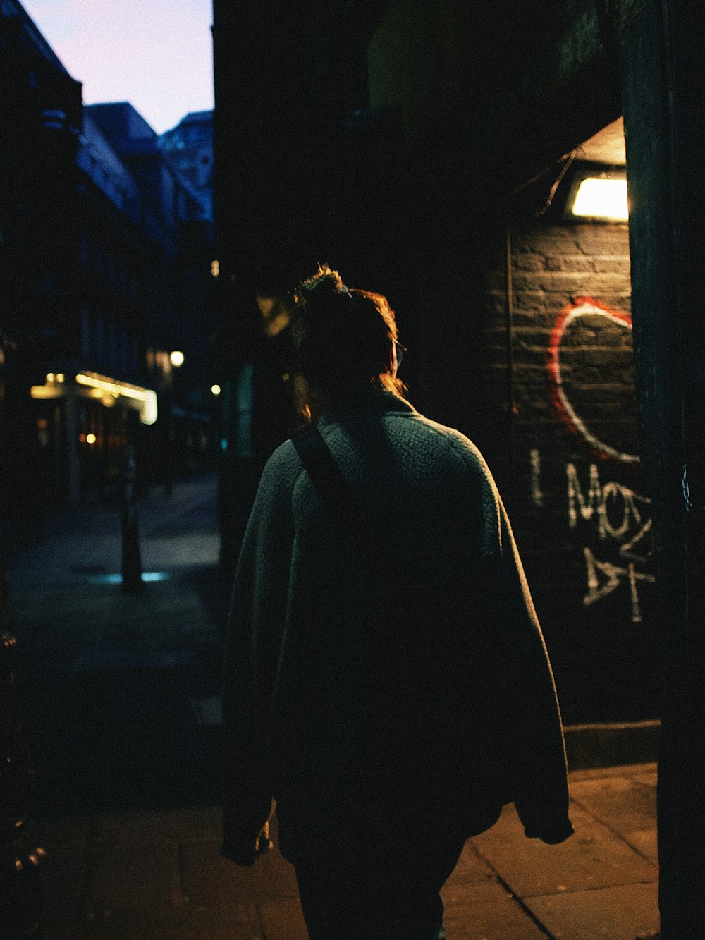 woman in gray coat standing near store during night time
