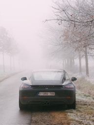 black car on road covered with fog