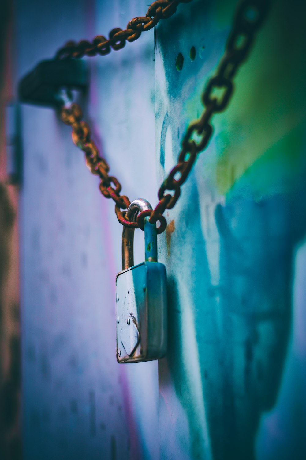 silver padlock on blue metal fence