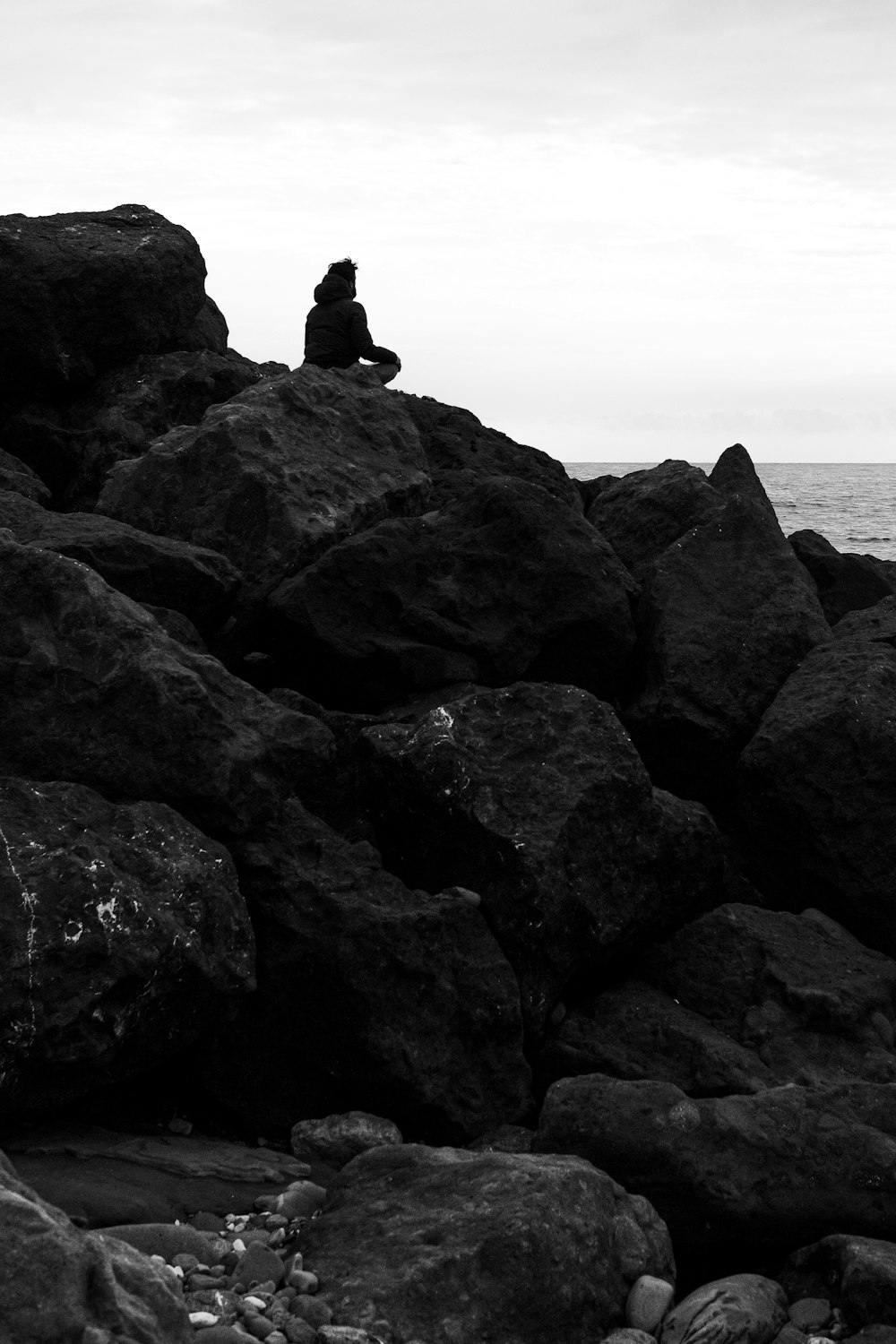silhouette of person sitting on rock formation during daytime