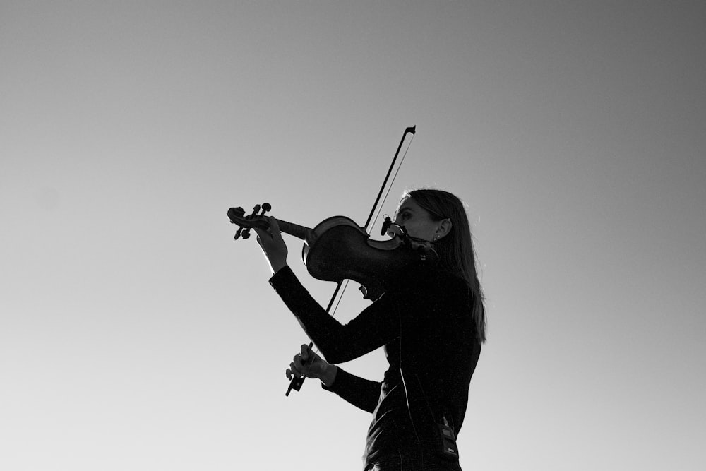グレースケールでバイオリンを弾く女性