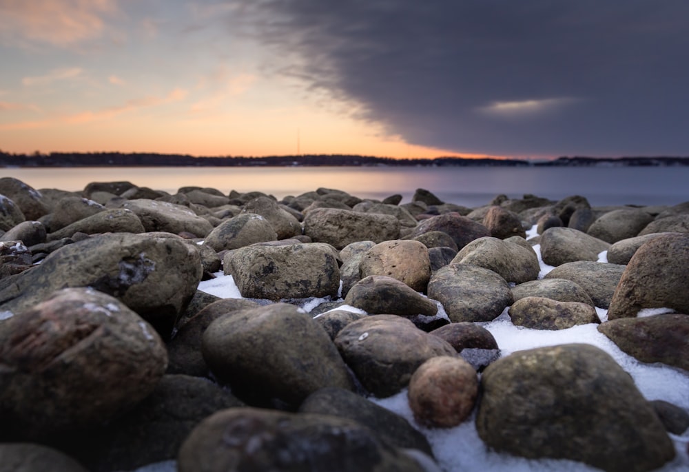 gray and black stones near body of water during sunset