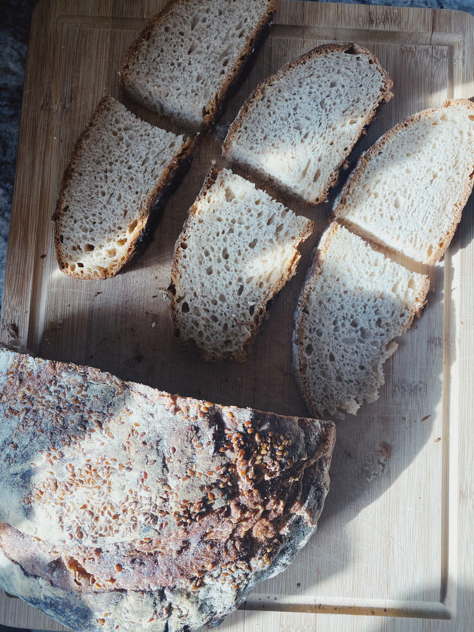 Wooden cutting board with four slices of crusty, quartered bread resting on their sides