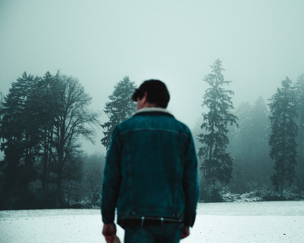 man in blue and black jacket standing on snow covered ground