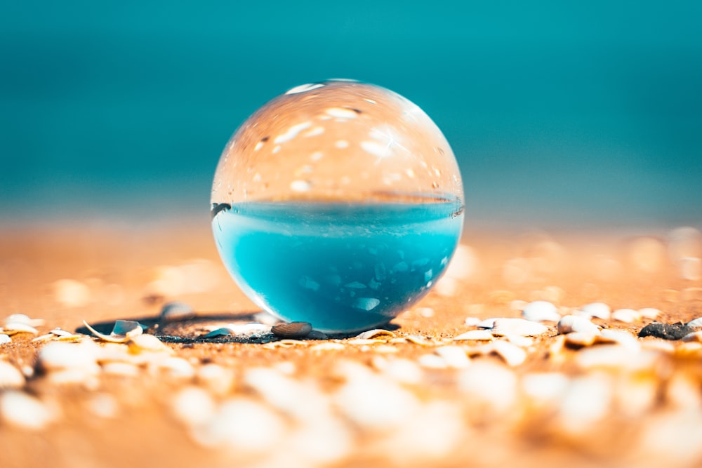 sfera di vetro trasparente su sabbia marrone durante il giorno