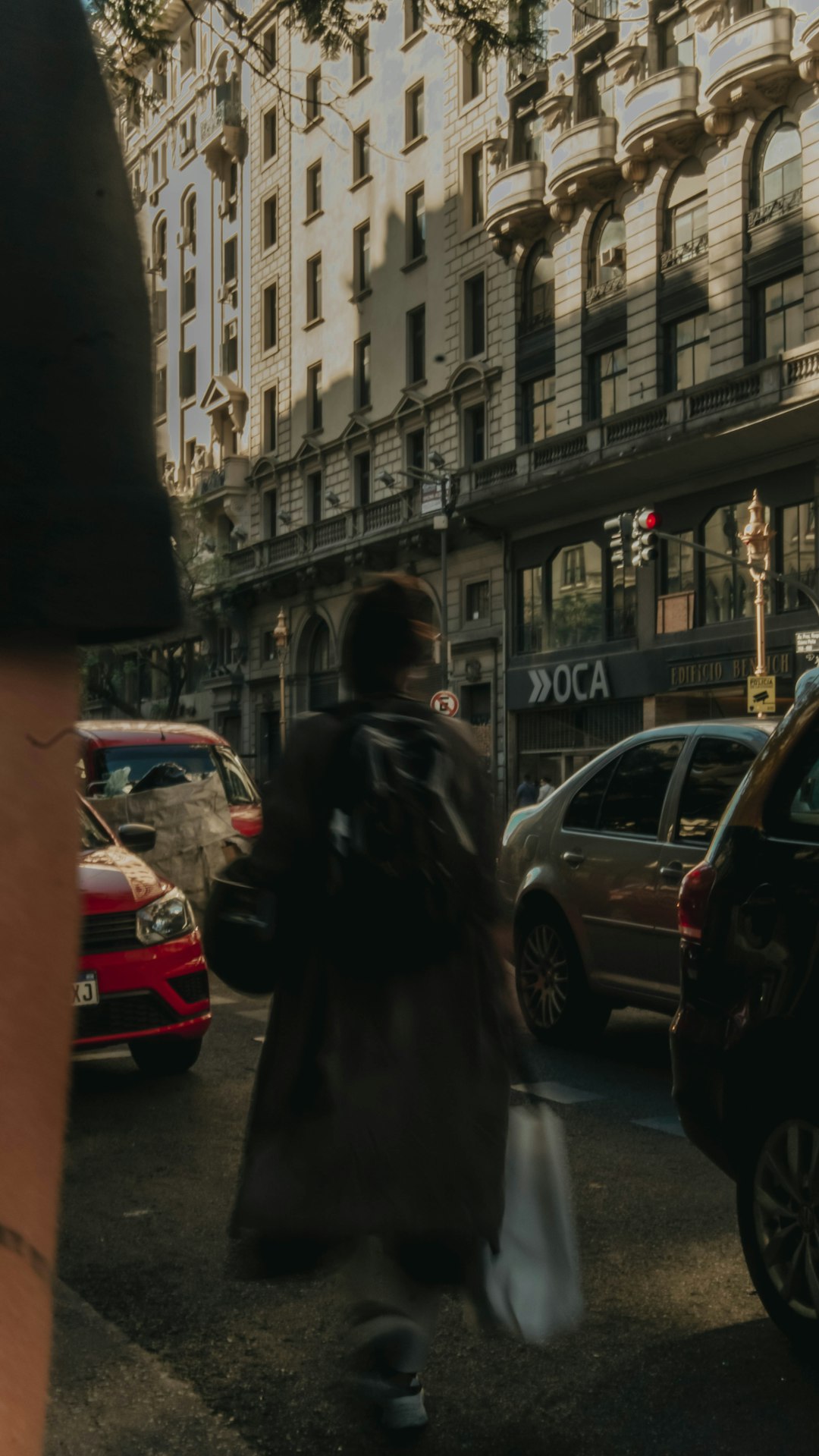 woman in black coat standing near cars and buildings during daytime