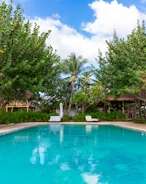 An inviting pool area surrounded by natural stone and soft beige tones under clear blue skies.