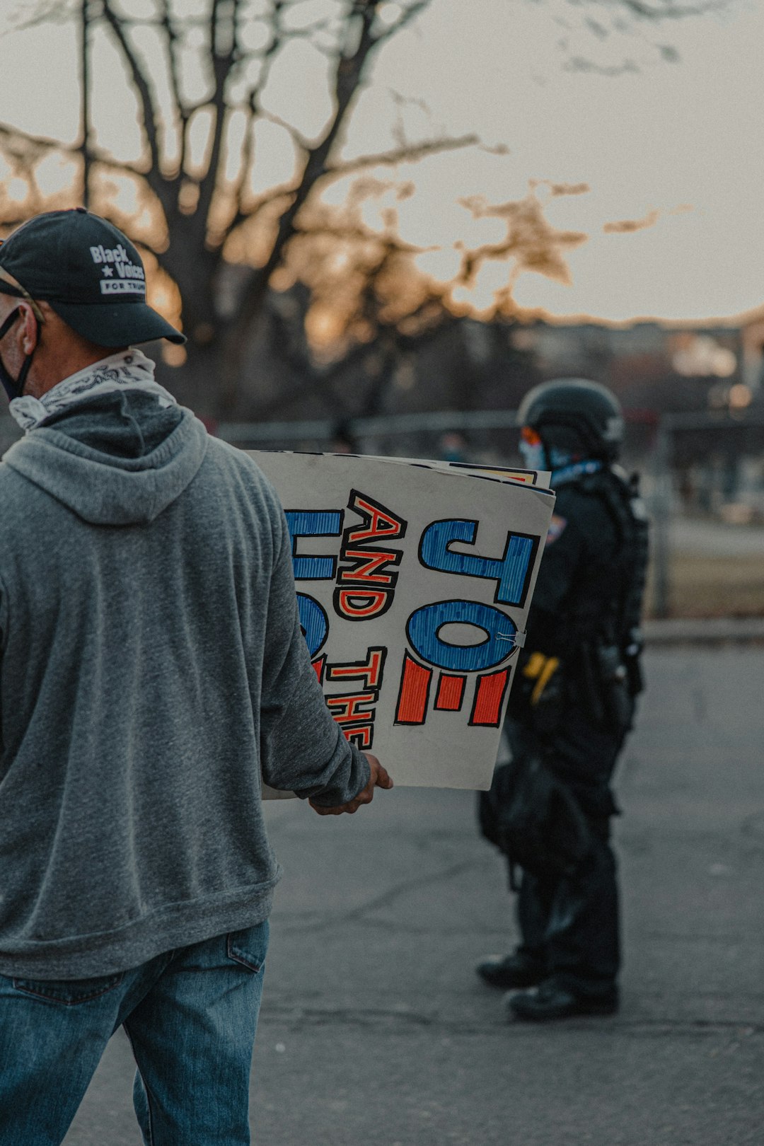 man in gray hoodie holding white and blue signage