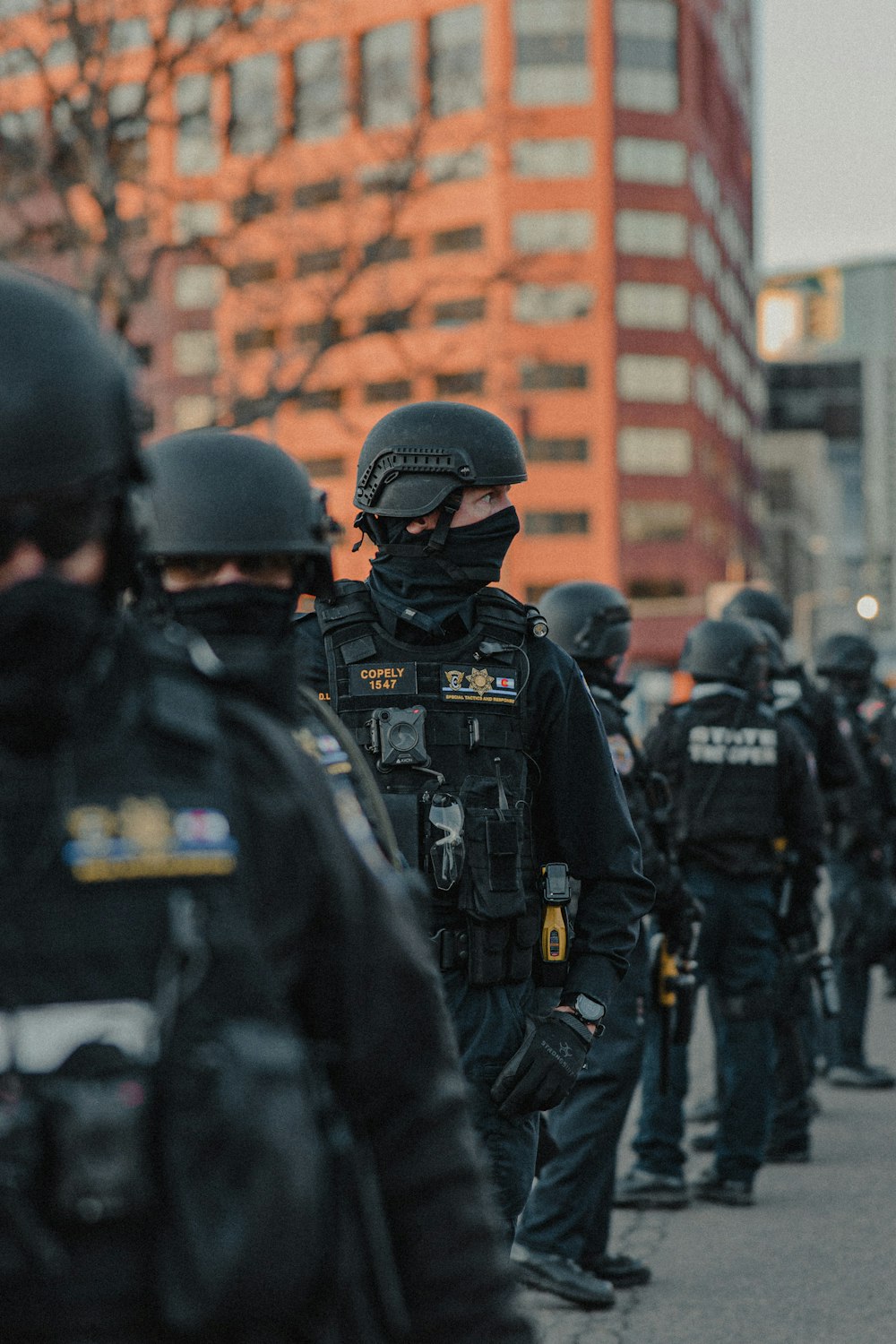 policial em pé em frente ao prédio de tijolos marrons durante o dia