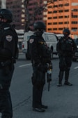 Tactical team in black uniforms coordinating an operation outdoors during dusk.