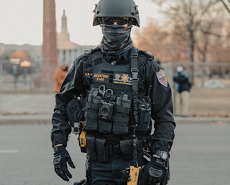 man in black and gray camouflage uniform holding black and brown rifle