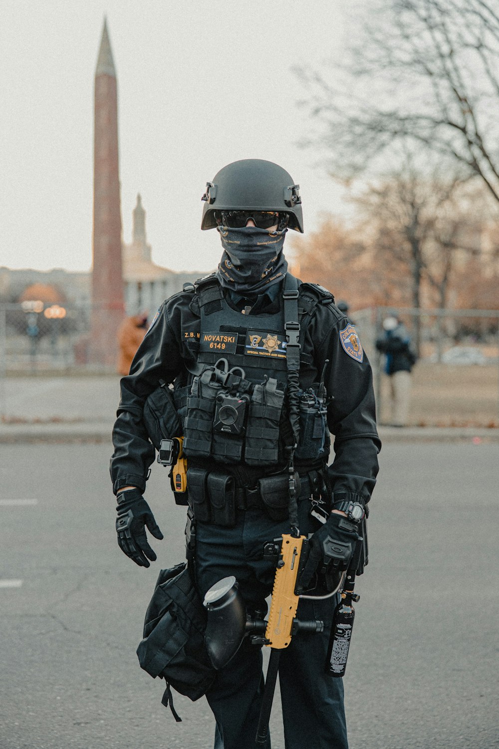 Hombre con uniforme de camuflaje negro y gris sosteniendo un rifle negro y marrón