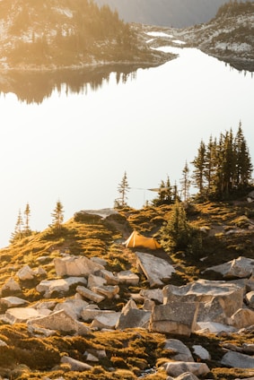 A cozy tent pitched beside a serene lake in the Canadian Rockies at sunrise