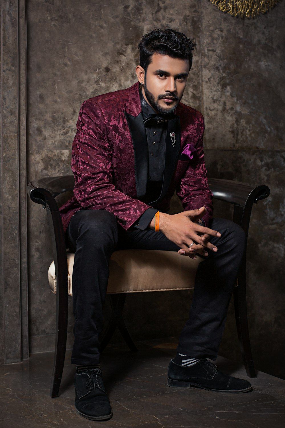 man in purple and black suit sitting on black armchair