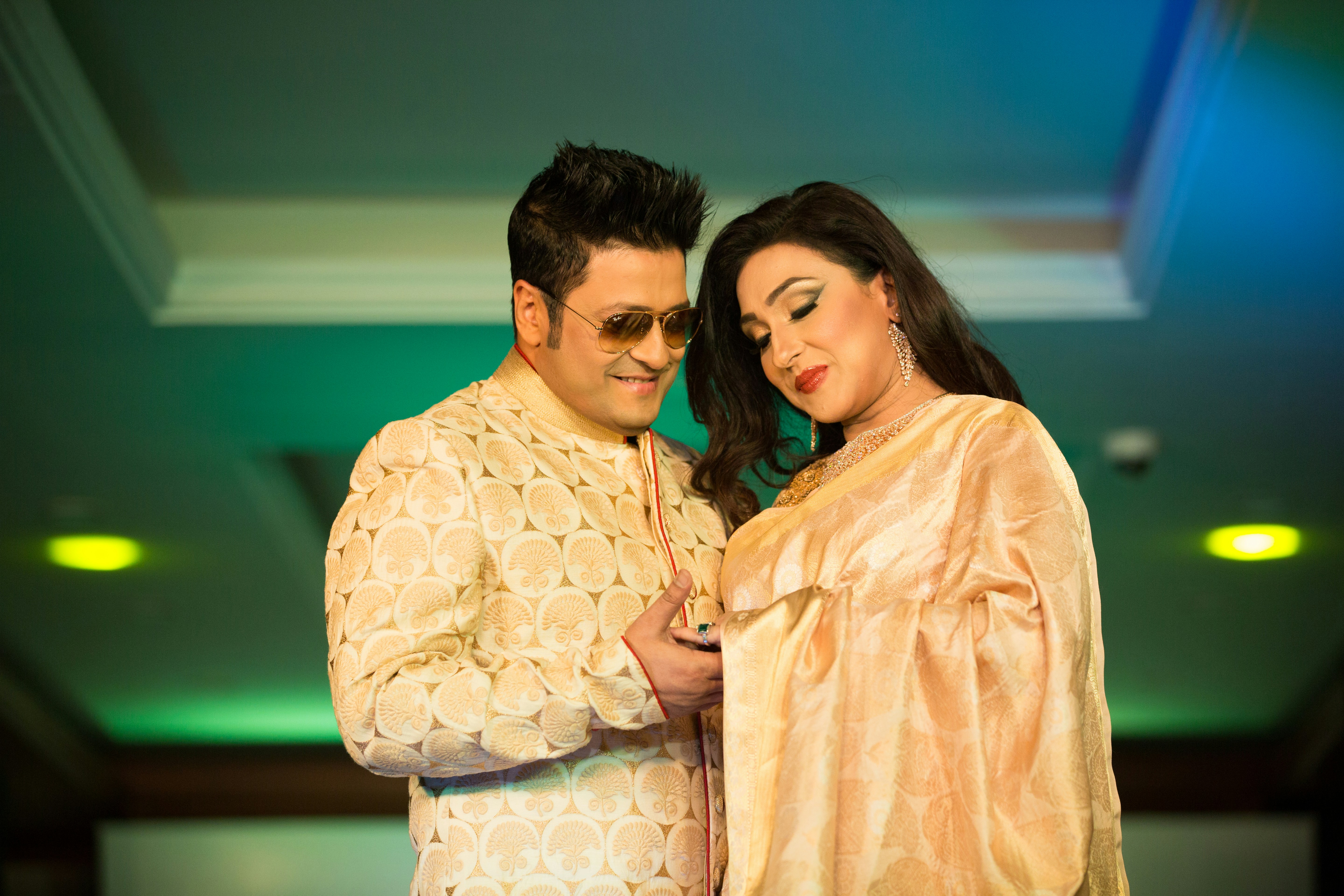 Elegant couple in formal Indian attire at a palace event, warm candlelit background