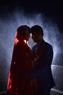 man in black suit kissing woman in red dress