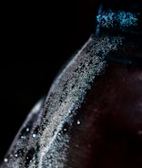 Close-up of a sparkling beverage bottle with condensation.