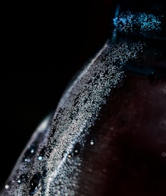 Close-up of a glass bottle filled with aqua di monte water, dew glistening on its surface.
