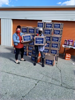 Hands exchanging a box filled with donated items outdoors