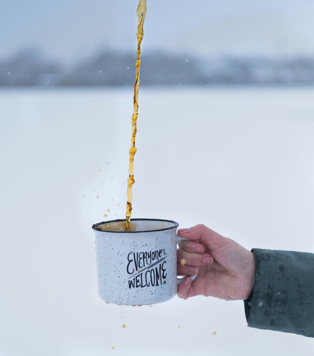 person holding white and blue ceramic mug with yellow string