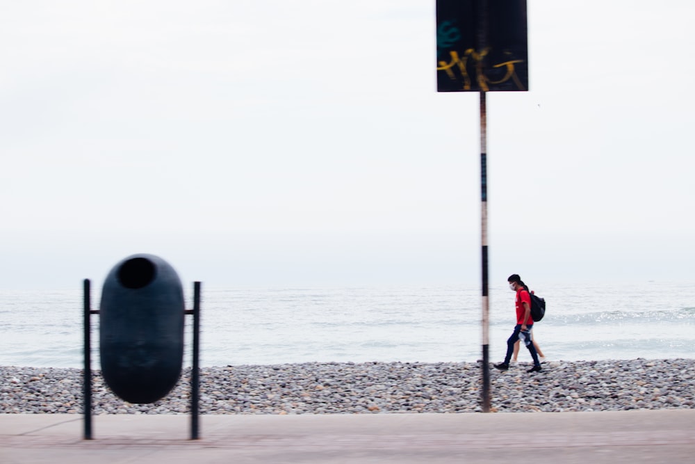 man in red jacket standing on beach during daytime