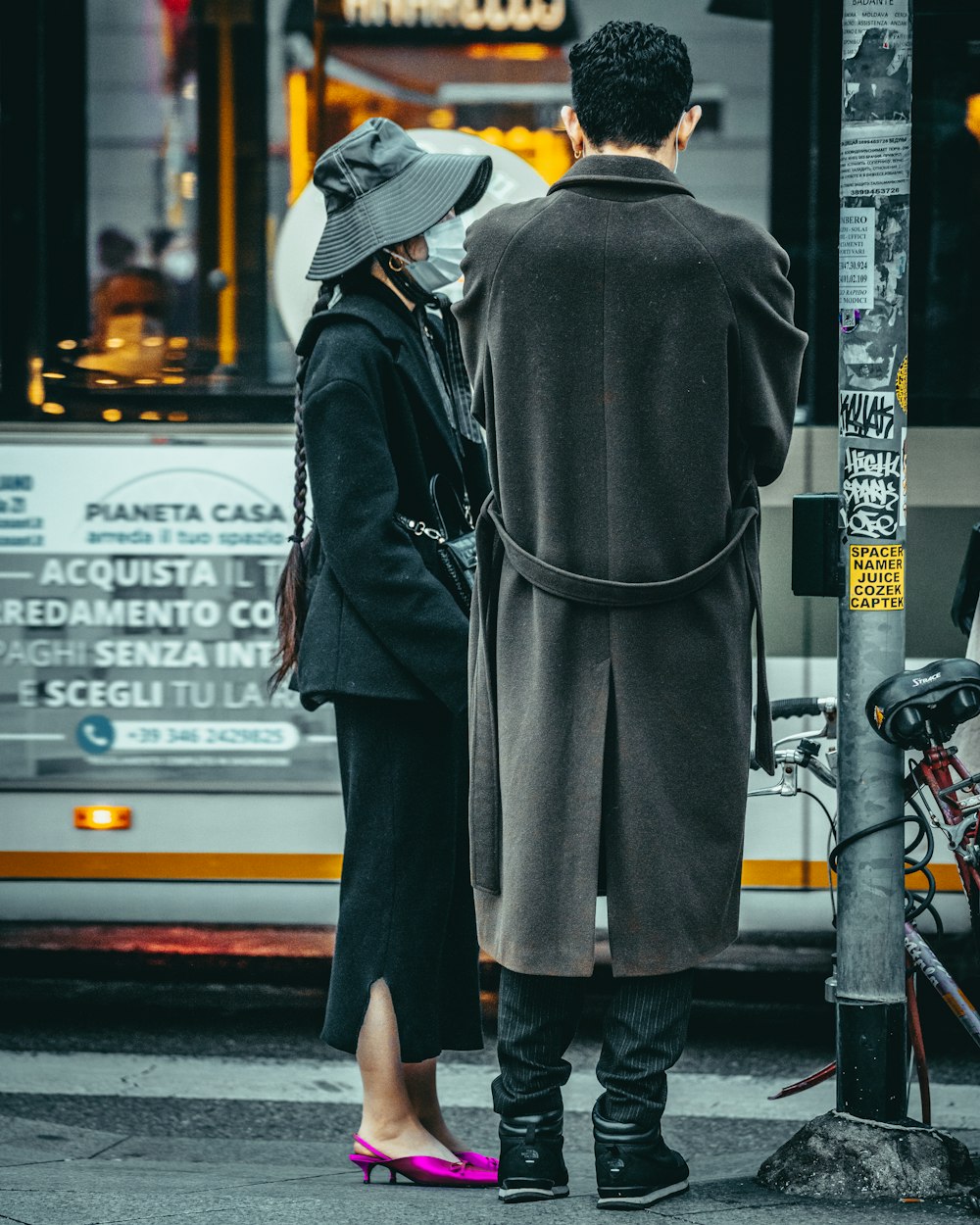 man in black coat and brown hat standing on sidewalk during daytime