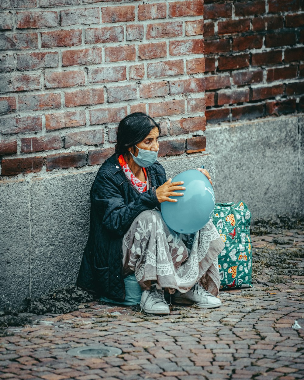 woman in black and brown floral dress sitting on brown brick wall during daytime