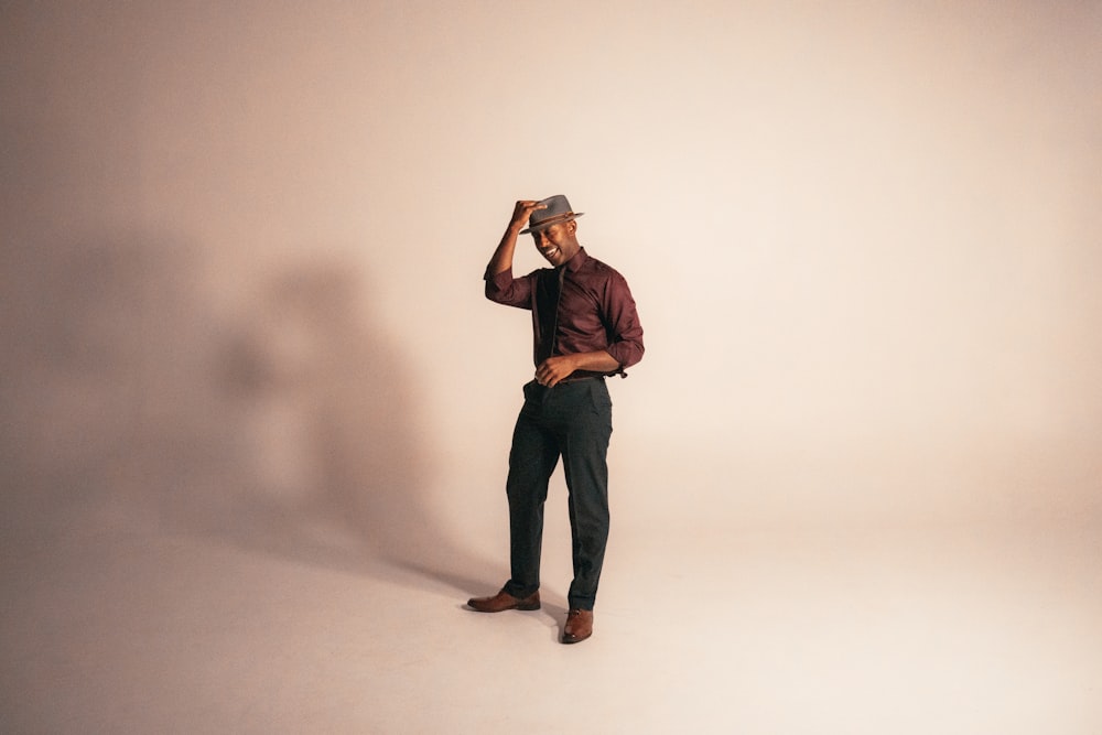 man in brown dress shirt and black pants wearing brown fedora hat