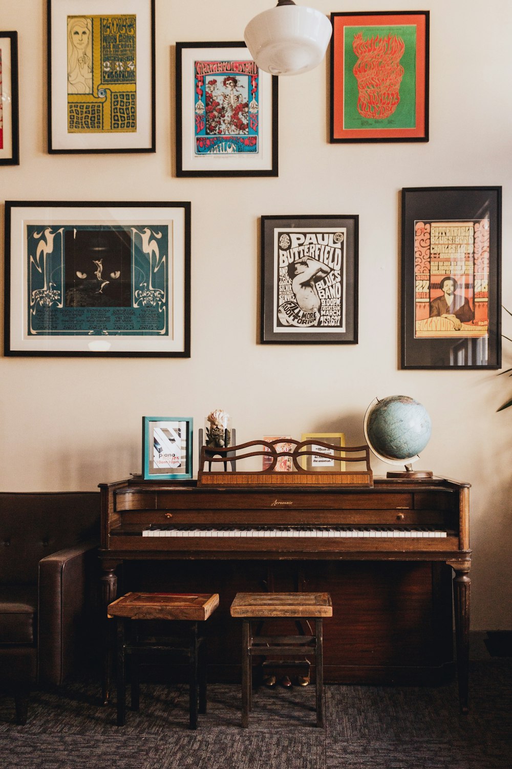 brown wooden upright piano beside black and white desk globe