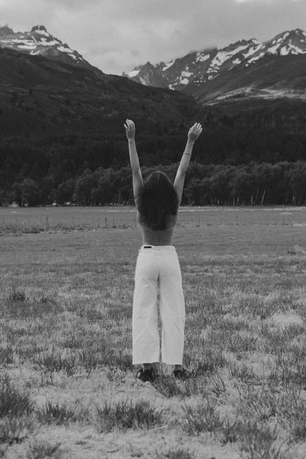 grayscale photo of woman in white dress standing on grass field