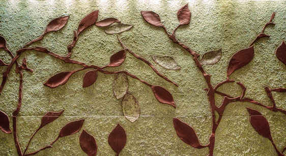 Close-up of vibrant abstract wall art featuring colorful leaves and flowers on reclaimed wood.