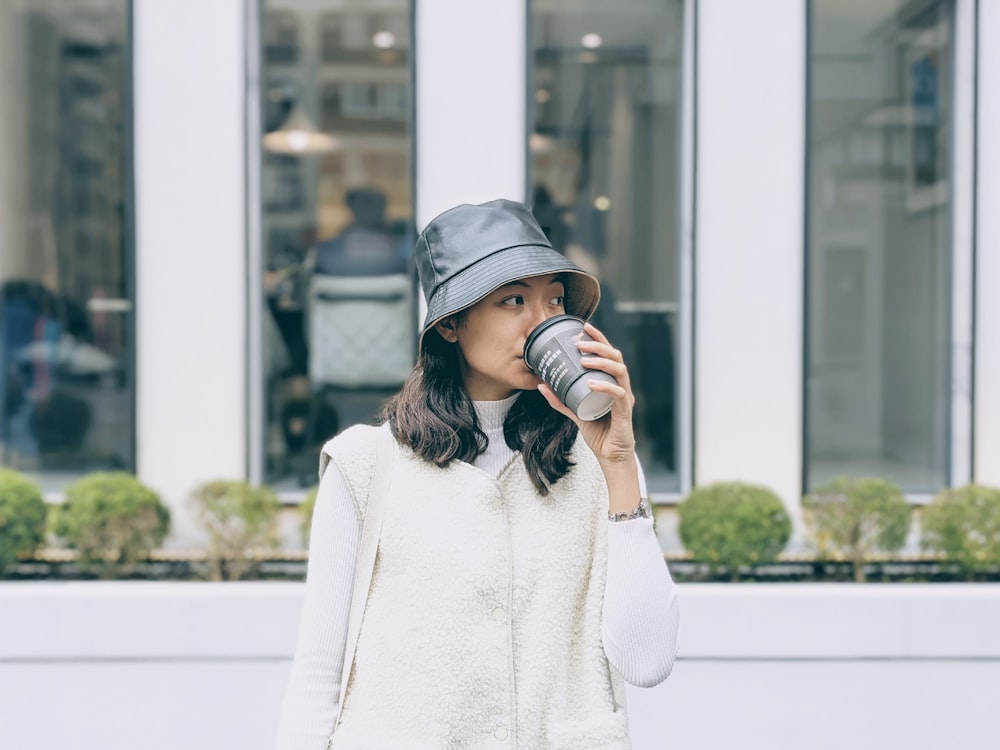 Frau in weißem Pullover mit schwarzer Mütze mit schwarzer DSLR-Kamera