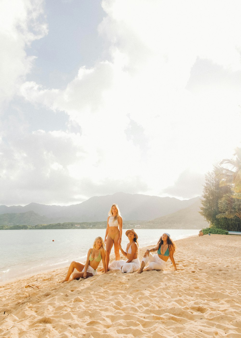 3 women in bikini sitting on beach shore during daytime